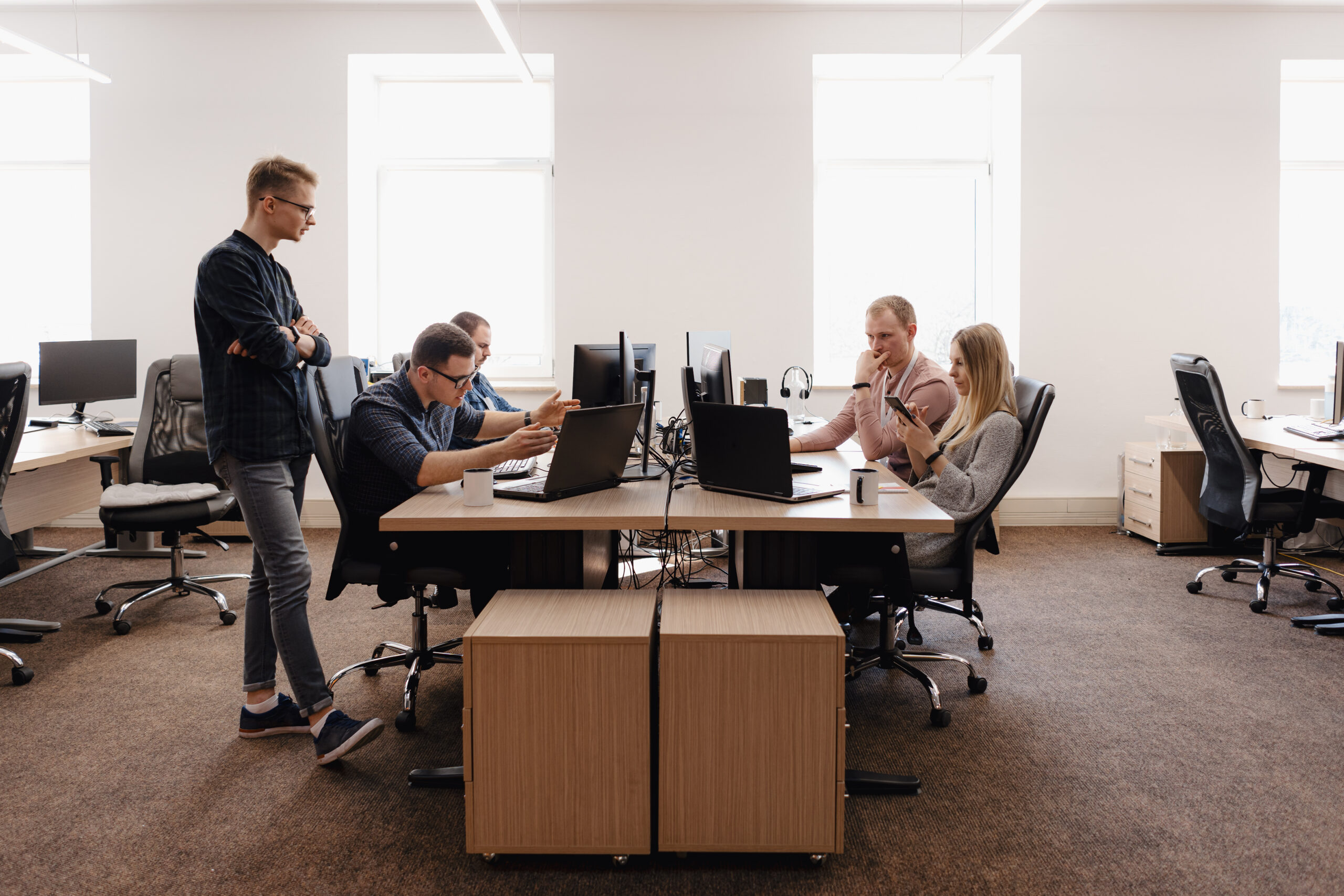 Full concentration at work. Group of young business people working and communicating while sitting at the office desk together with colleagues sitting in the background